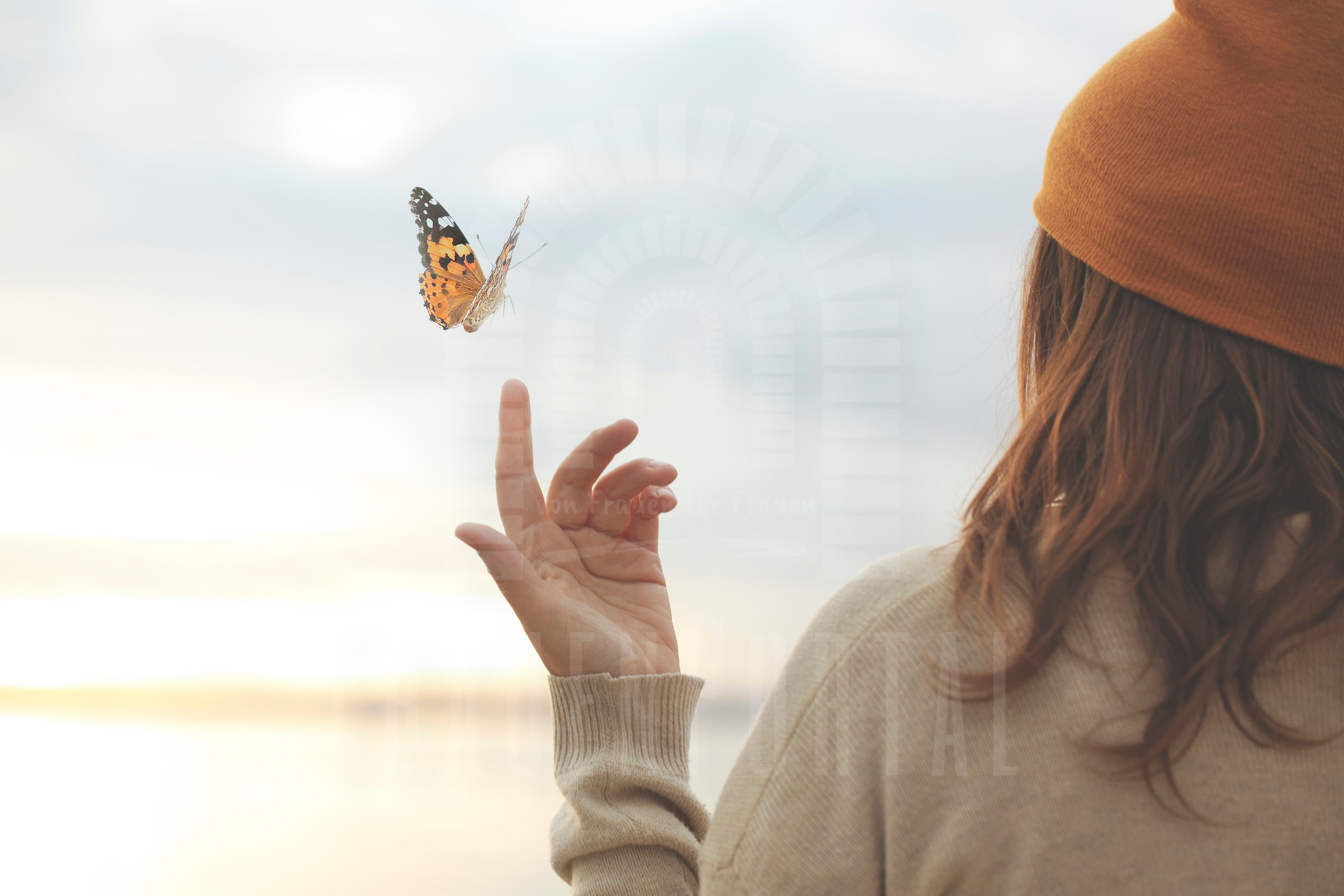 Frau hält ihre Hand in die Höhe, ein Schmetterling fliegt darüber